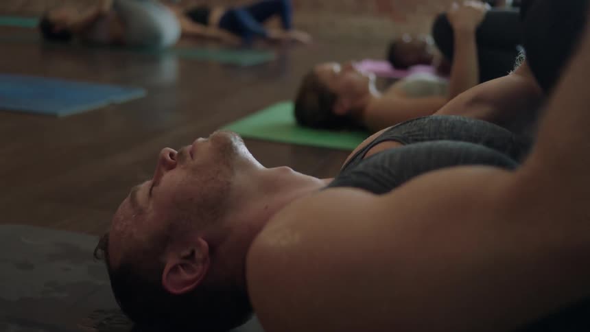 A man and group of women stretch and do yoga