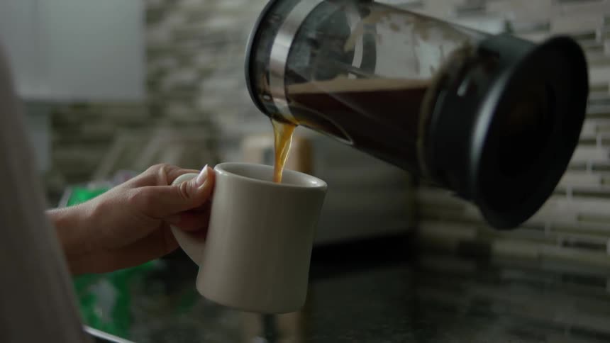 A woman is pouring coffee into a mug