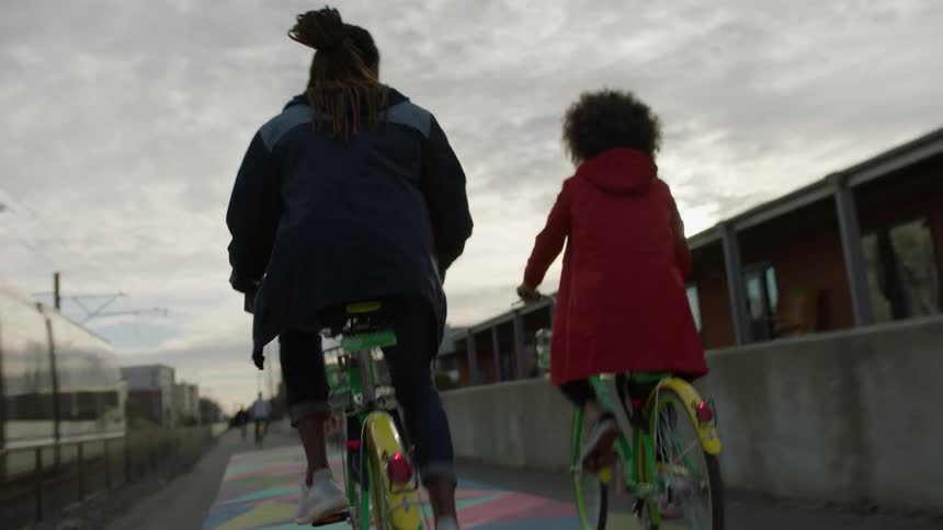 A man and woman bicycle alongside a moving city train