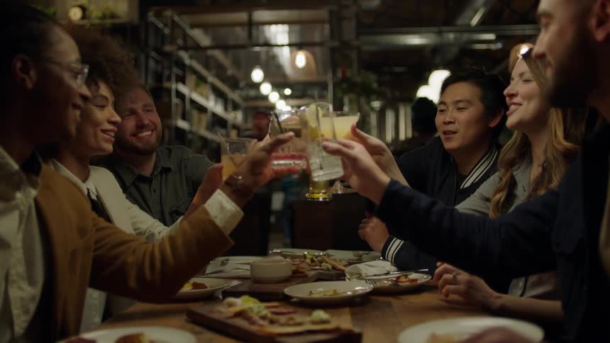 Friends sitting at table toast with their glasses and drink
