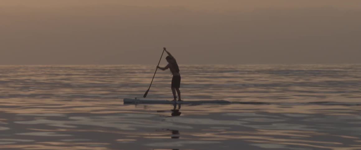 A man paddles a stand up board out in the ocean