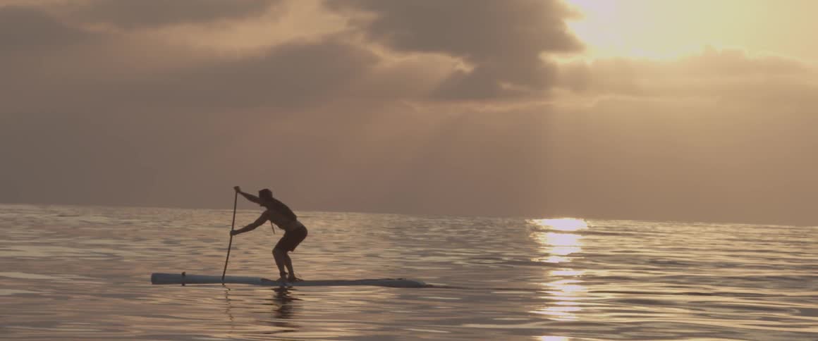Man on a paddle board in the ocean on a cloudy day