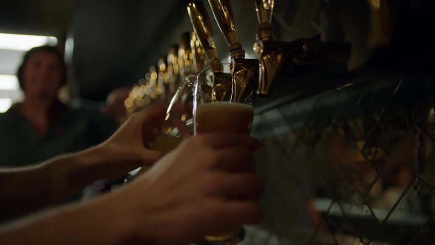 People are filling glasses with beer from taps