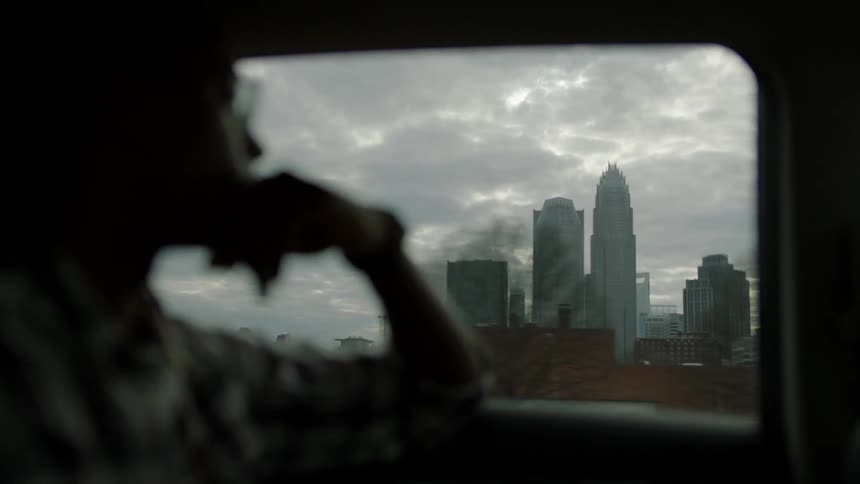 A man looks out the window of a moving vehicle while traveling in a city