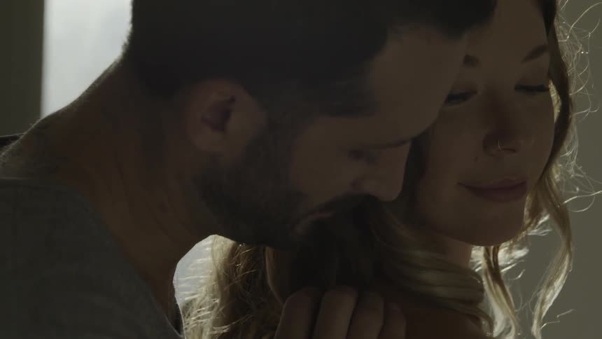 Man rubs woman's shoulder in bright sunlight