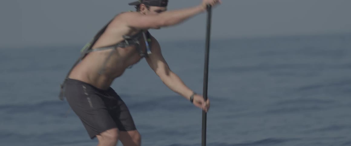 A man paddles on a board in the ocean