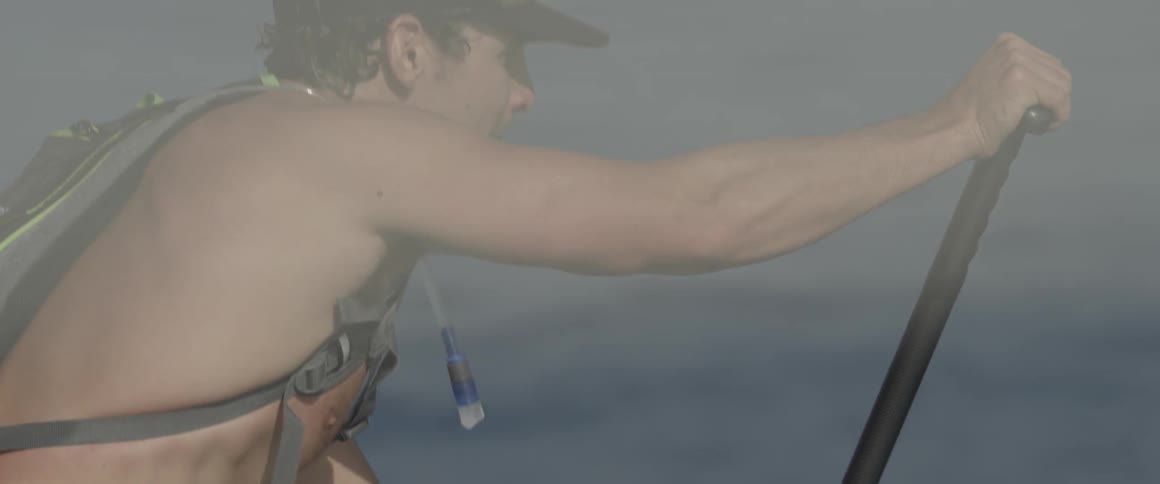 A man in a harness paddles through some water