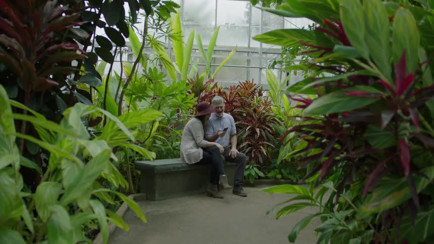 A man and woman talk on a bench in an indoor garden
