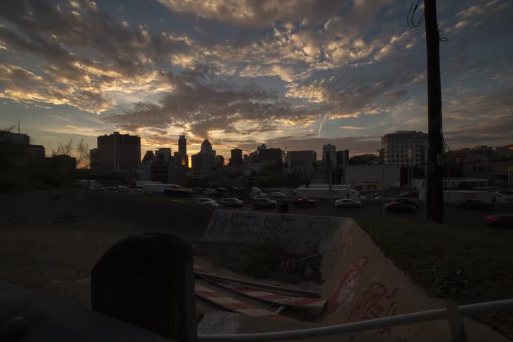 Cars drive on a city street at sunset