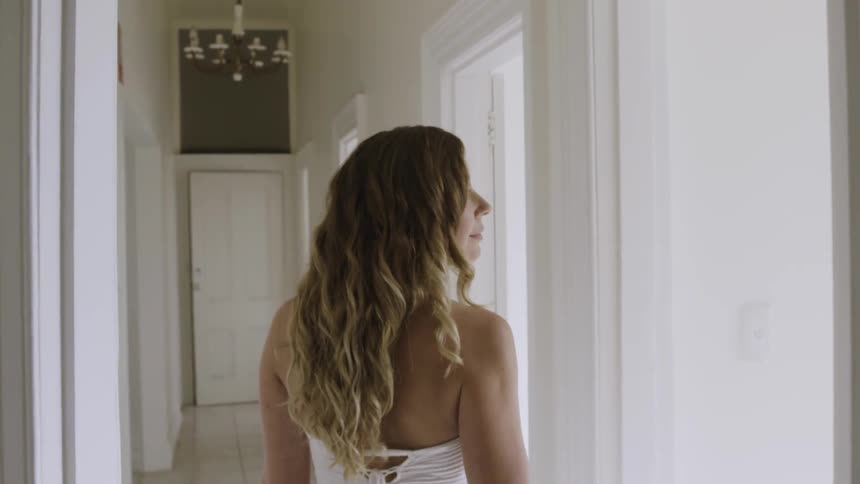 Blond woman wearing white walks through a doorway