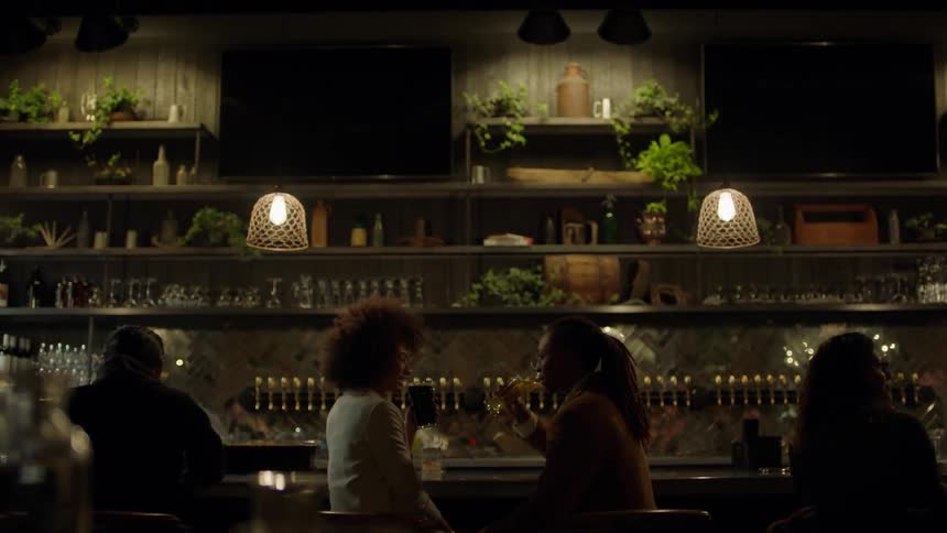 Two people toast drinks at a bar