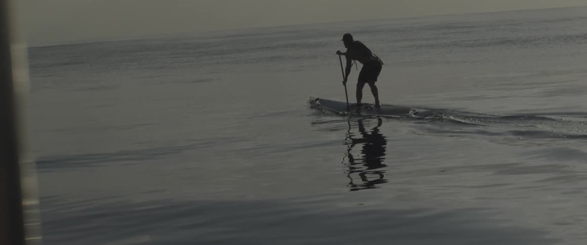 A man paddles on a surfboard