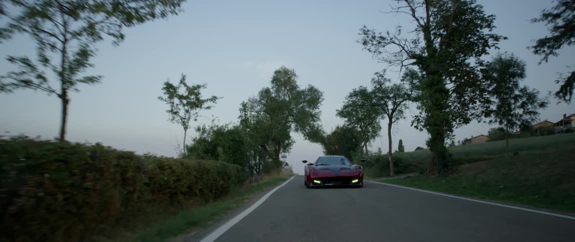 A sports car drives on a rural road at sunset