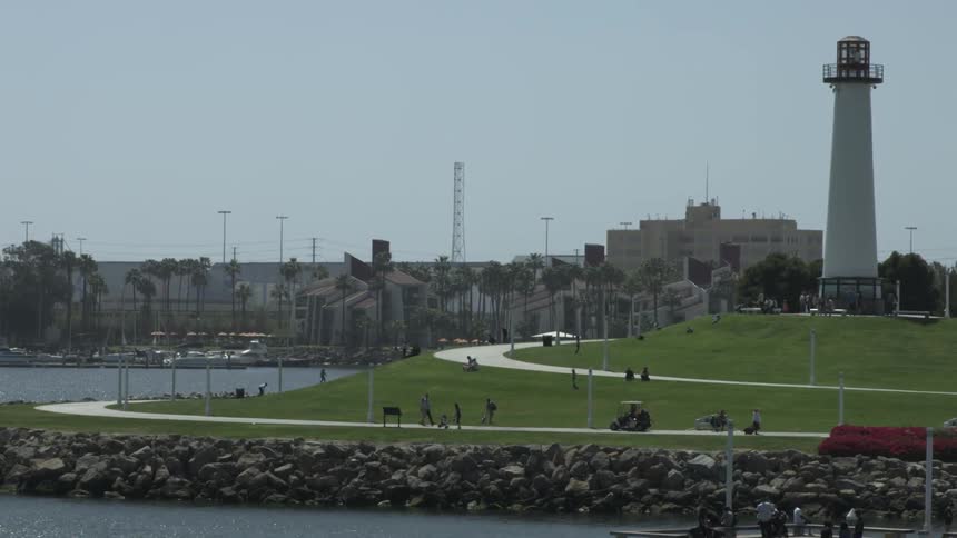 People walk along pathways near a lighthouse