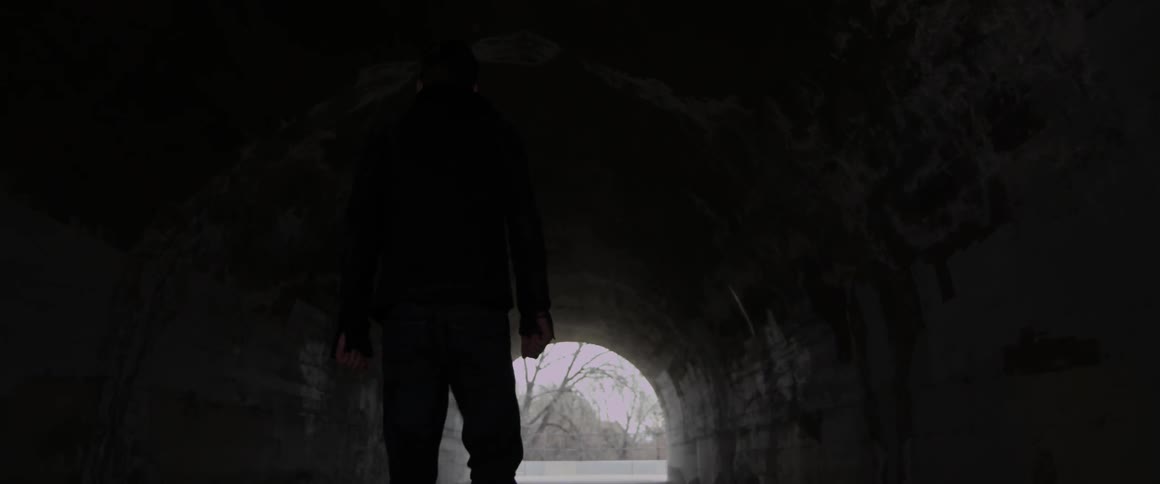 A man is walking through a tunnel
