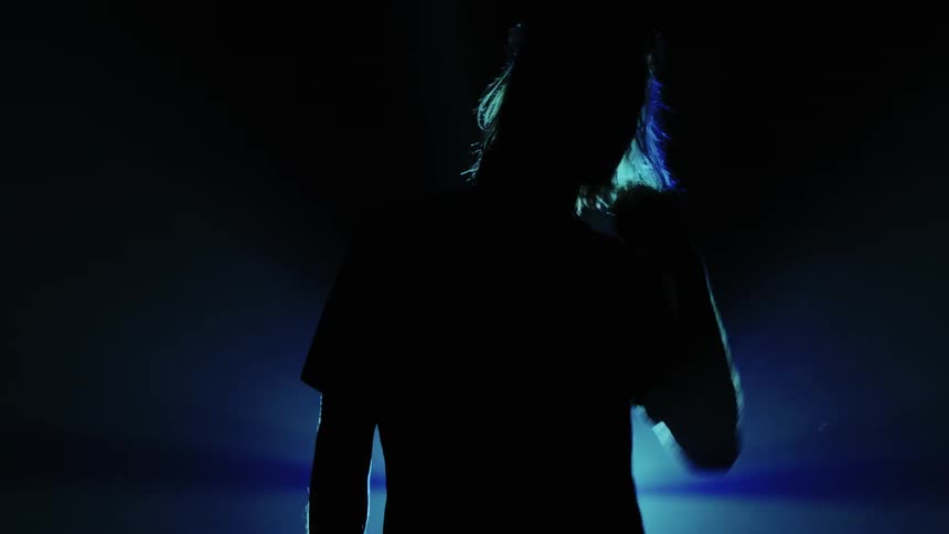 A man stands in front of a blue flashing light
