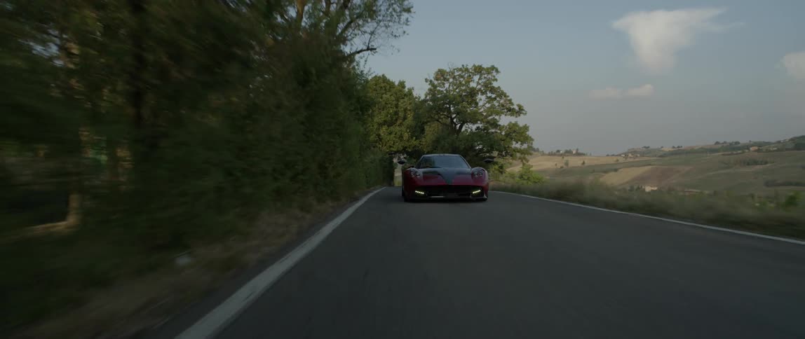 Sports car driving down a country road during the day