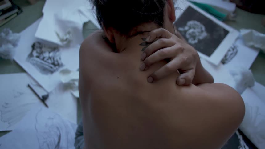 A woman leans forward and rubs her back