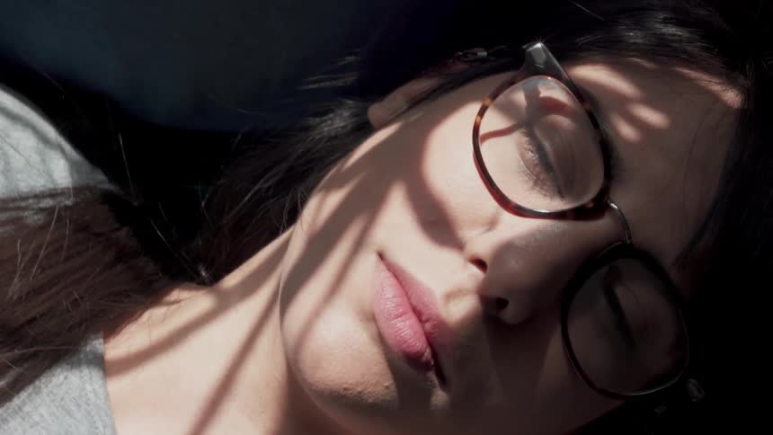 A woman wearing glasses opens her eyes
