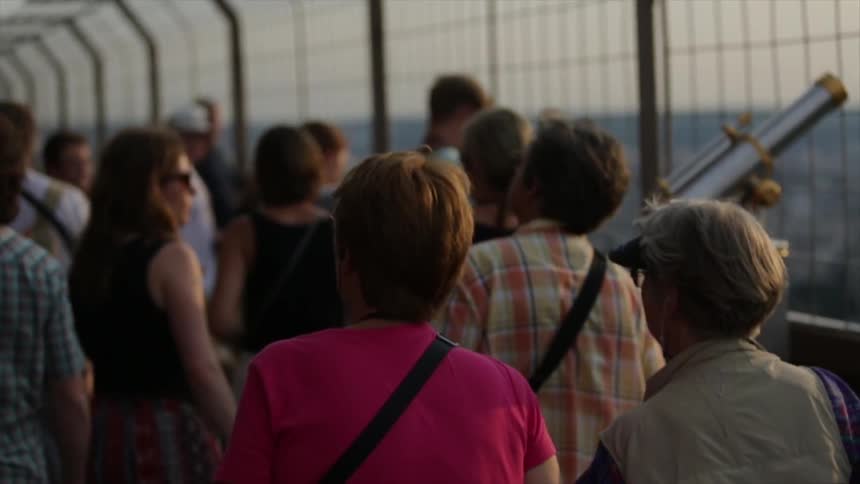 Tourists walk along the roof of a tall building taking in the view