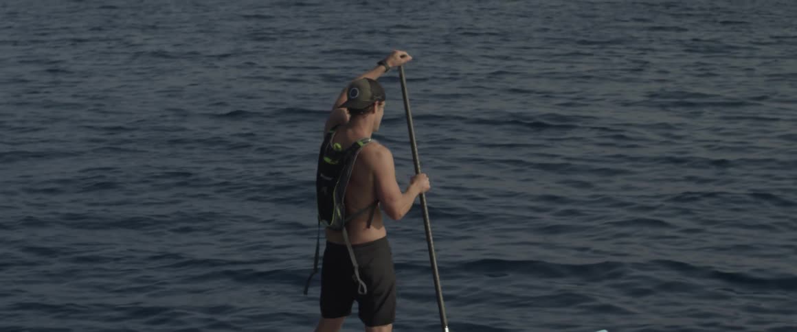 A man is paddling on a light colored canoe