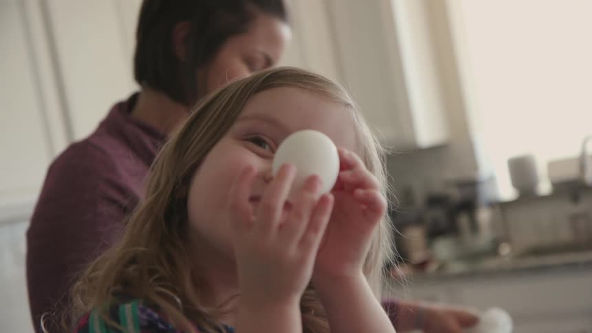 A young girl smiles while holding an egg