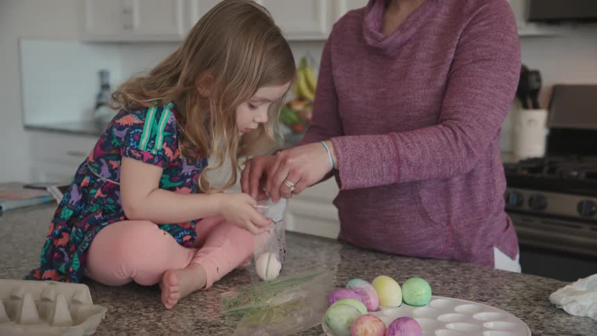 Woman and daughter decorate easter eggs