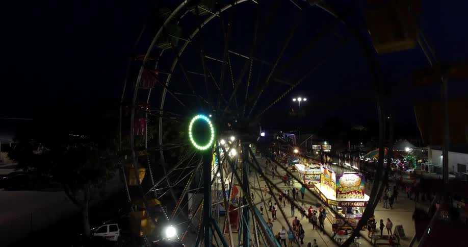 The carnival is brightly lit with many people at night