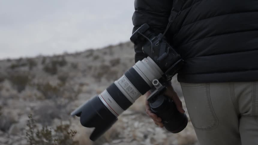 A photographer carries a camera outdoors