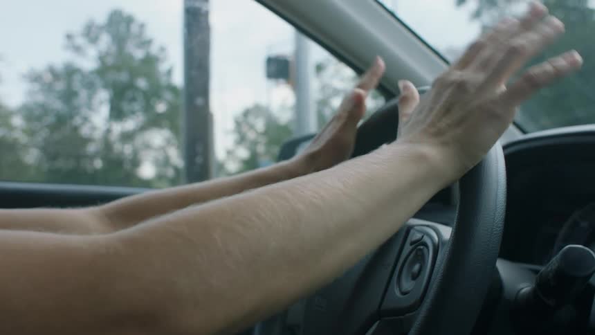 A person grips the steering wheel of a car