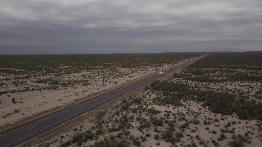Vehicles drive on a remote road on a cloudy day