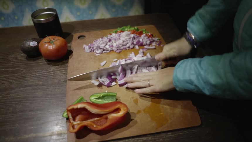 A woman dices onions on a cutting board