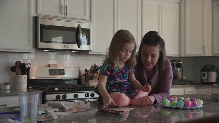 A mother and child are decorating dyed eggs
