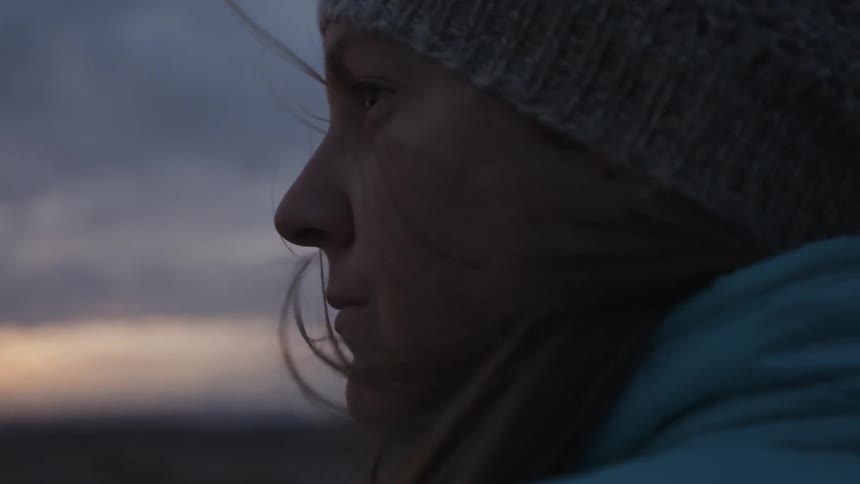 A woman looks around while wind blows her hair