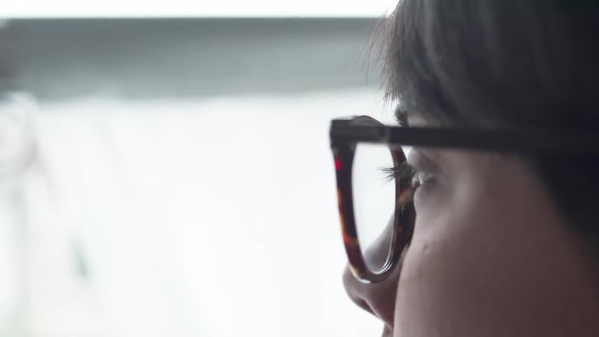 A woman wearing glasses looks outward