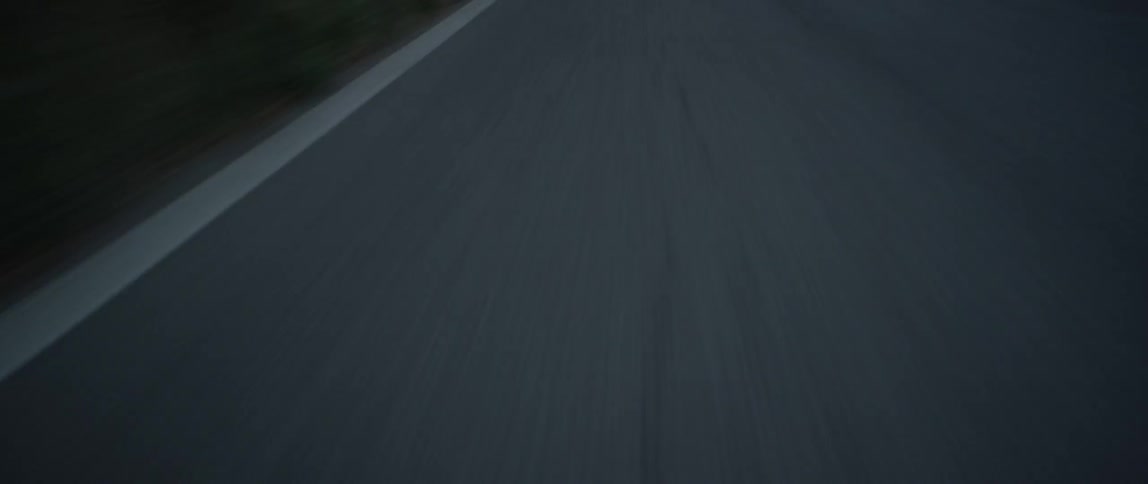 Road lines pass as a vehicle drives down the road