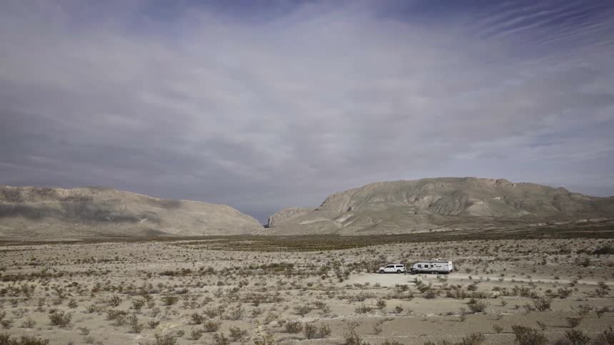 A truck with a trailer attached sits parked in the desert