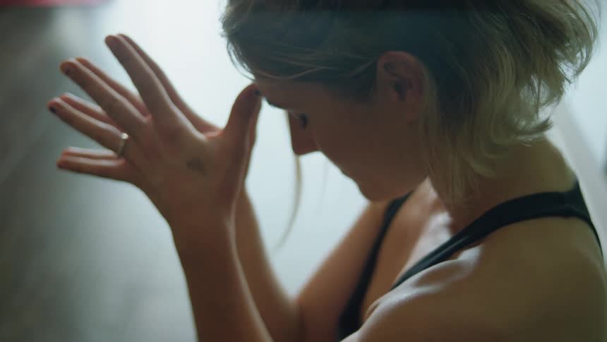 Woman holding hands together at forehead meditating with eyes closed