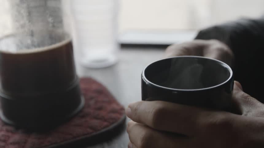 A person grips a cup of coffee