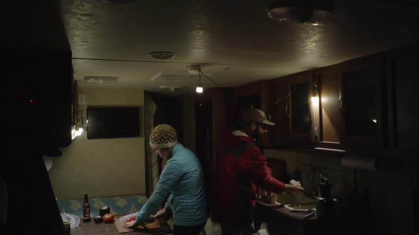A man and woman cook in a camper's kitchen