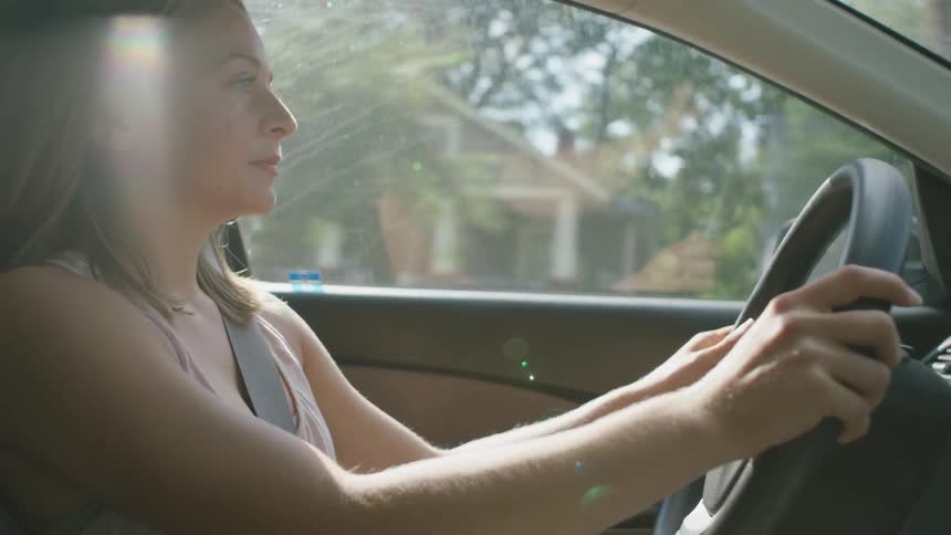 Woman holding steering wheel with both hands as she drives a vehicle