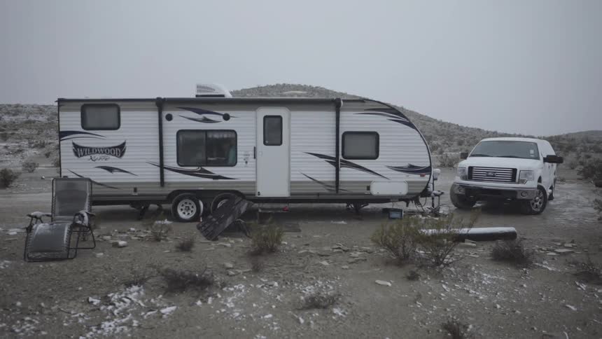A truck is parked near a caravan in the desert