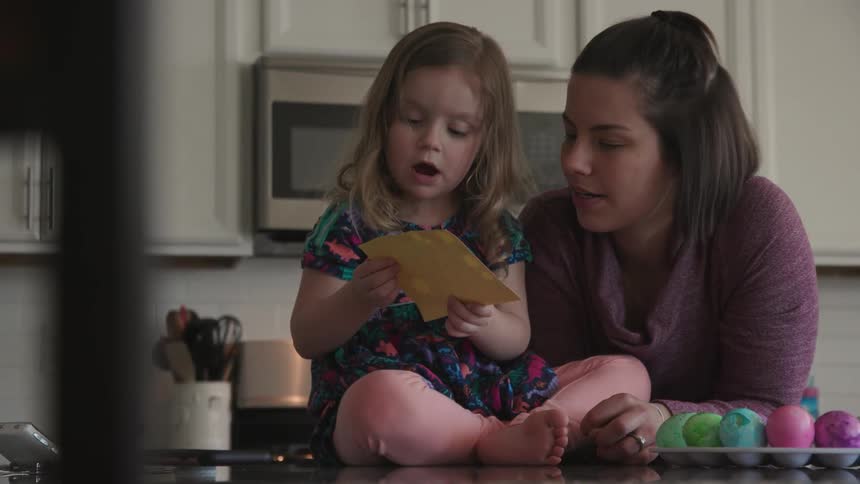 A mother and child are decorating dyed eggs