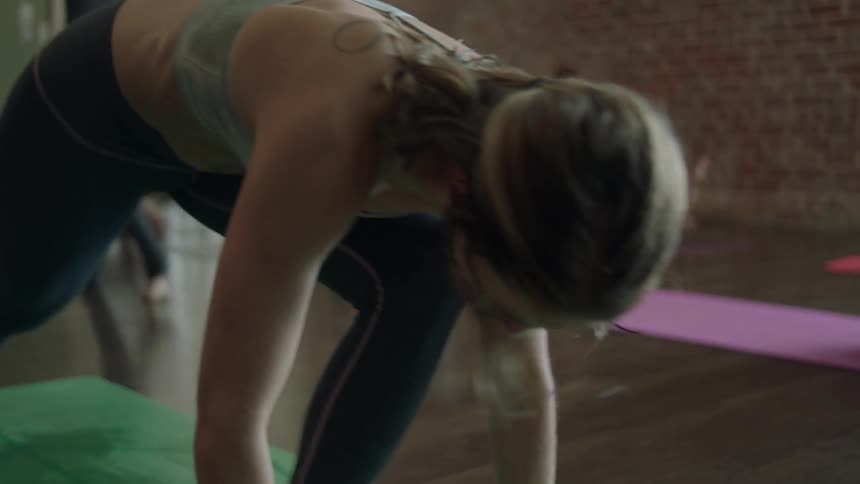 A woman doing yoga in a class changes positions