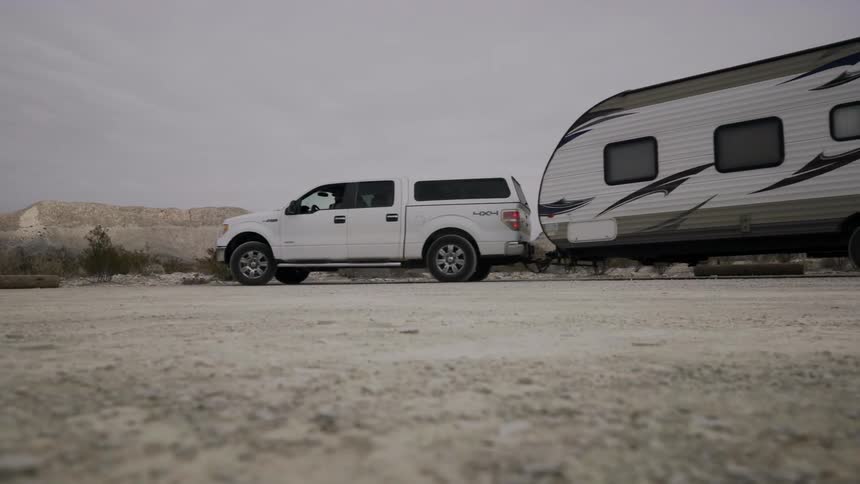 A truck pulls a camper behind it in the wilderness