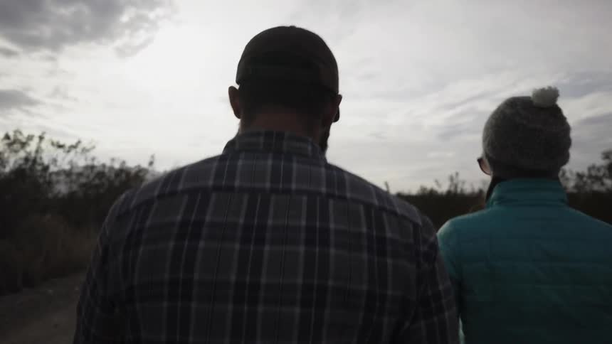 Man and woman walk among tall grass