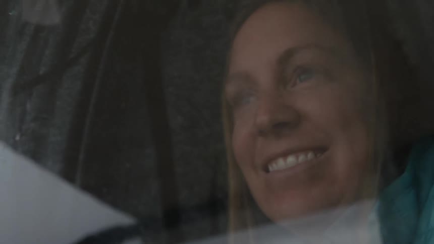 A woman laughs and smiles looking out a window