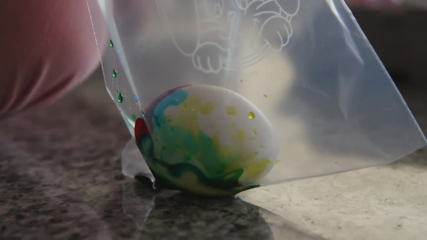 A child pours dye on an egg