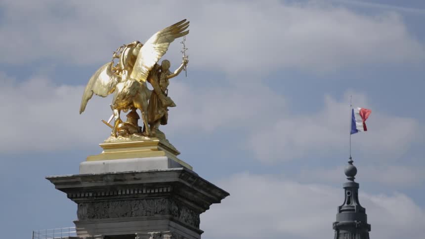 A flag blows in the wind near a monument statue