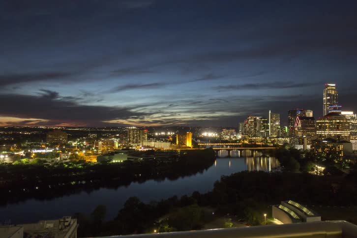 City lights illuminate the night sky as the sun sets
